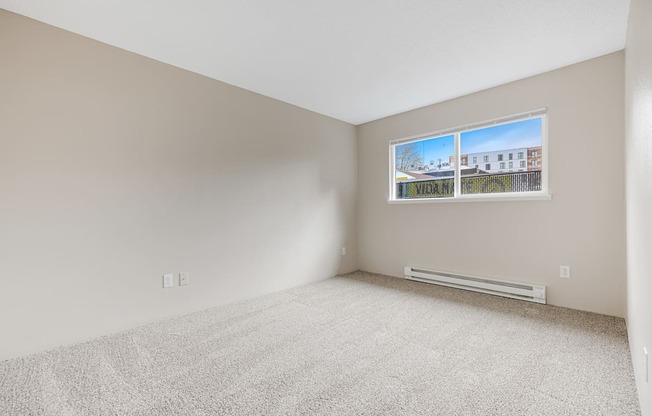 A room with a window showing a view of a street with houses.