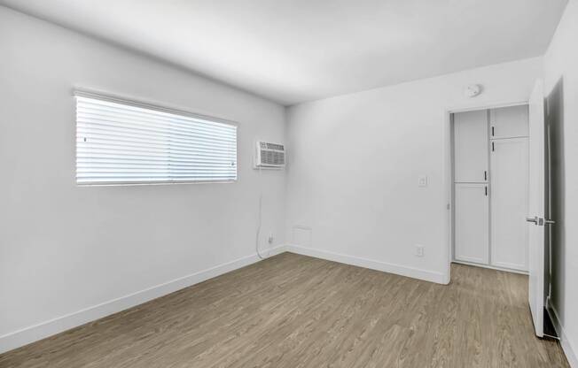 the living room of an apartment with white walls and wood floors