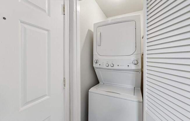 A white washing machine is in a small space between a door and a wall.