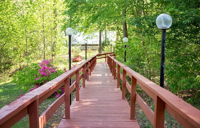 A wooden bridge with railings and lamp posts on either side.