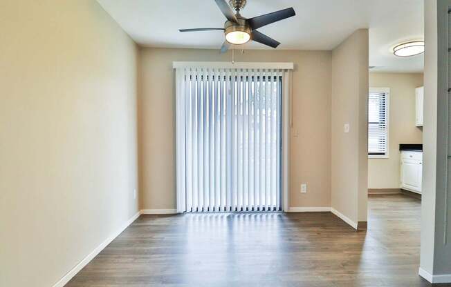 A room with a ceiling fan and a window with blinds.