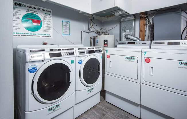 A row of white front load washing machines are lined up in a laundry room.