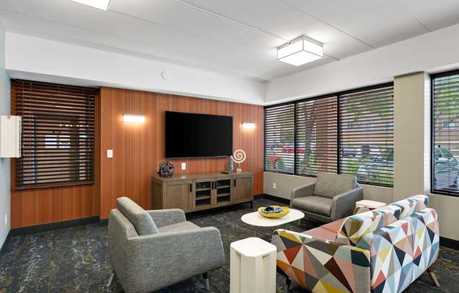 A modern living room with a grey sofa, a grey armchair, a wooden cabinet, a TV, and a coffee table.