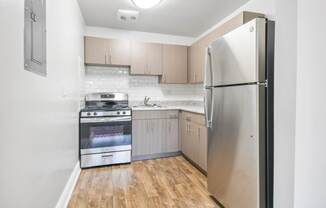 A kitchen with a stainless steel refrigerator, oven, and wooden floors.