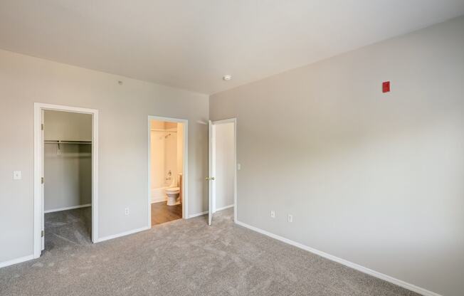 a bedroom with a carpeted floor and a door to a bathroom