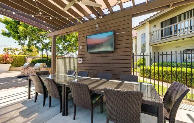 Outdoor dining area and TV adjacent to grill