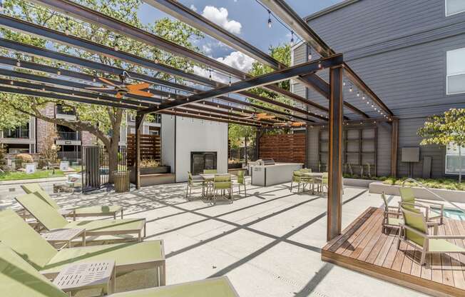 a patio with a fireplace and a pergola with chairs and tables