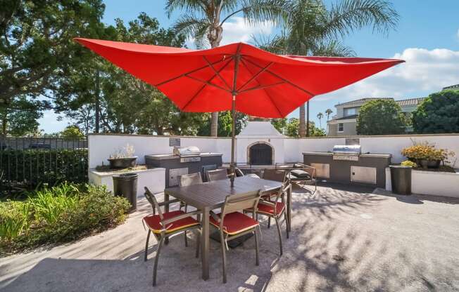 a patio with a table and a red umbrella