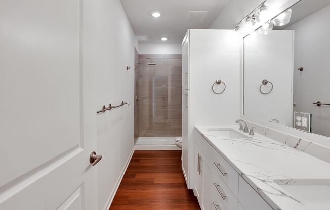 a bathroom with white cabinets and a shower and a sink and a mirror