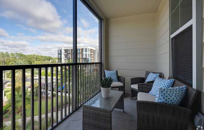 A balcony with a table and chairs overlooking a parking lot.