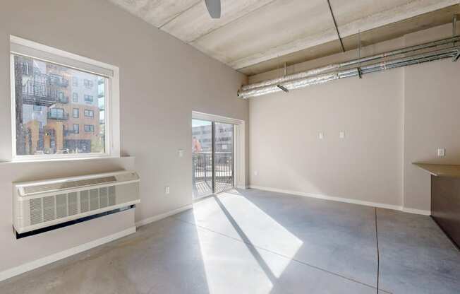 an empty living room with a large window and concrete floors