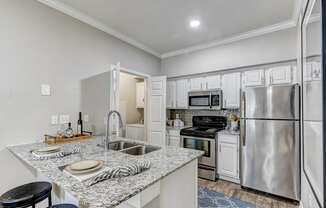 A kitchen with a granite countertop and stainless steel appliances.