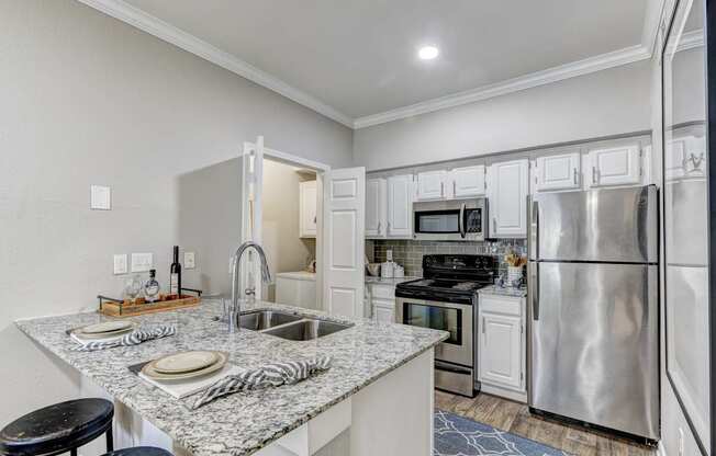 A kitchen with a granite countertop and stainless steel appliances.