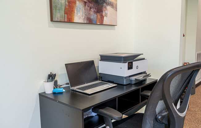 an office desk with a laptop computer and a printer on it