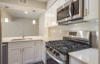 a kitchen with white cabinets and stainless steel appliances