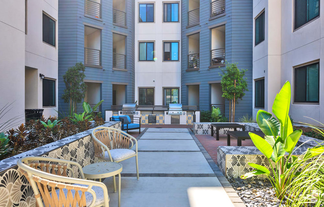A courtyard with chairs and plants in front of apartment buildings.