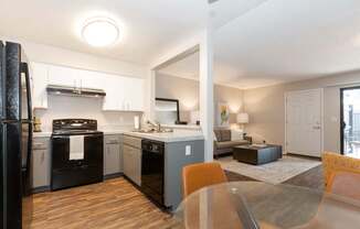 A modern kitchen with a black refrigerator and wooden floors.