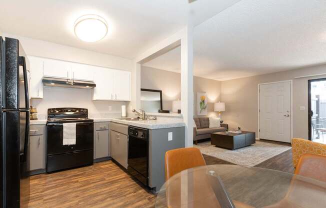 A modern kitchen with a black refrigerator and wooden floors.