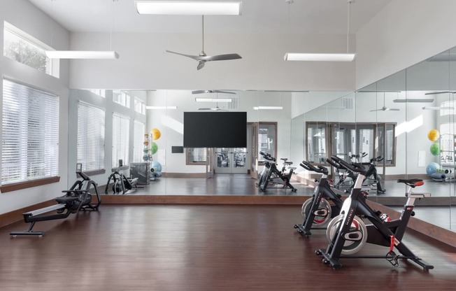 a workout room with exercise bikes and a tv