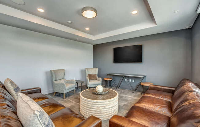 A living room with brown leather couches and a flat screen TV mounted on the wall.