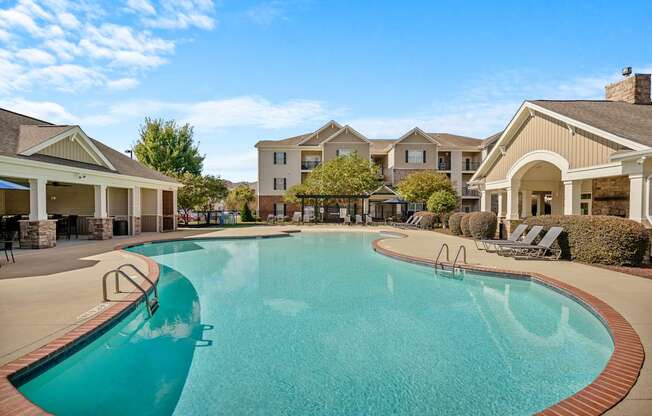 A large swimming pool in front of a building with a clear blue sky.