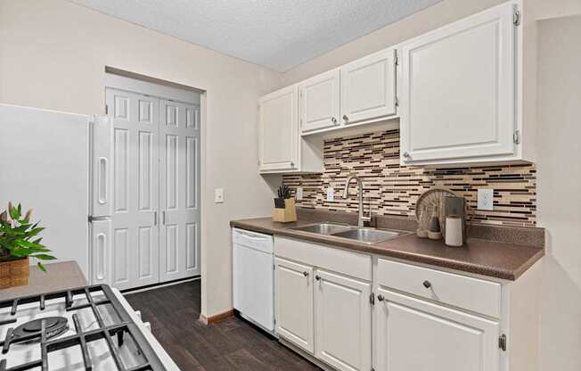 A kitchen with white cabinets and a white fridge.