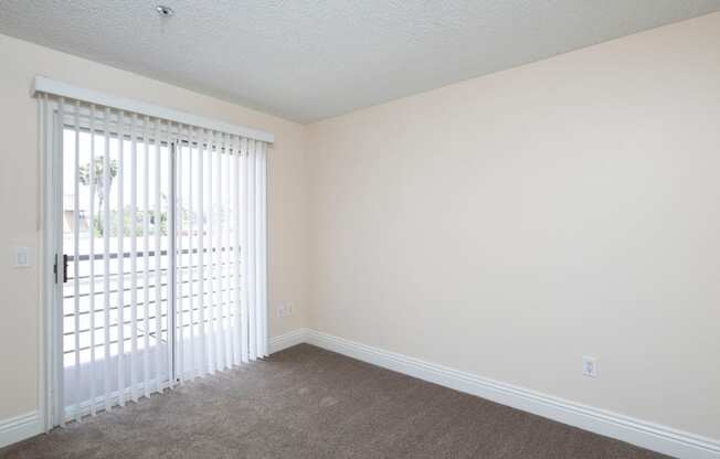 Carpeted bedroom with balcony at the Atrium Apartments in San Diego, California.