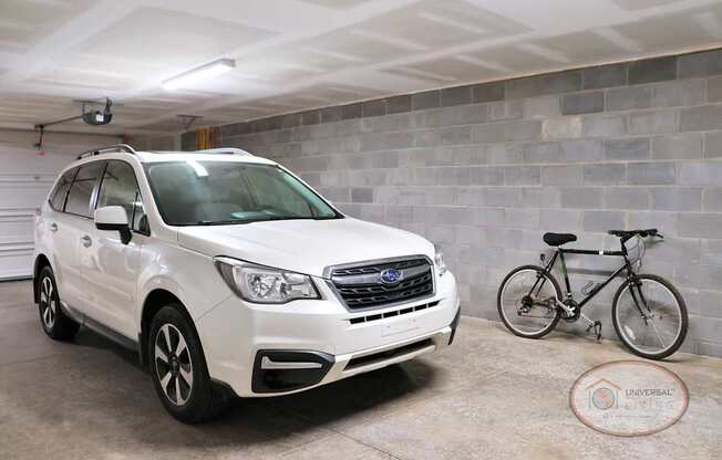 A white SUV is parked in a garage next to a bicycle.
