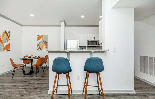 a kitchen and dining area with chairs and a counter with a microwave