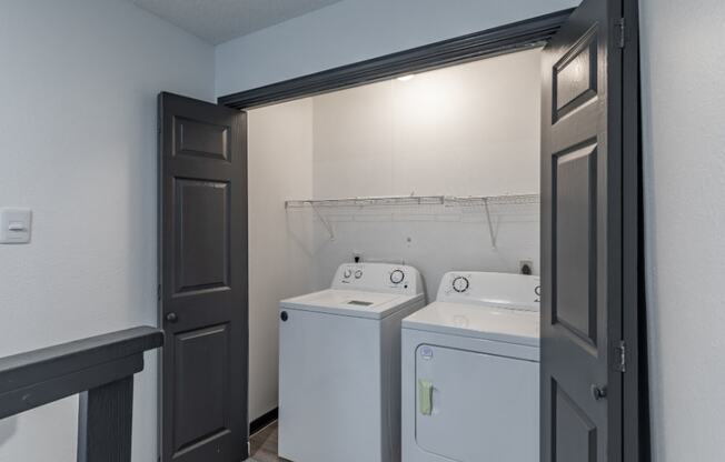 a laundry room with two washing machines and a door to a closet