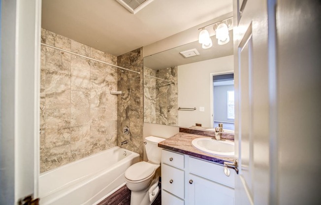Tiled Bathroom with Tub and White Cabinets