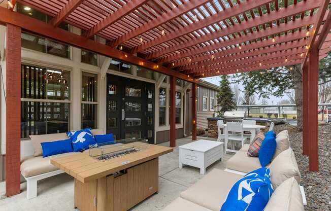 A wooden pergola with a table and chairs underneath it.