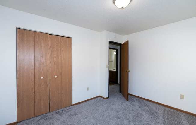 a bedroom with a closet and carpeted floors. Fargo, ND Pacific South Apartments