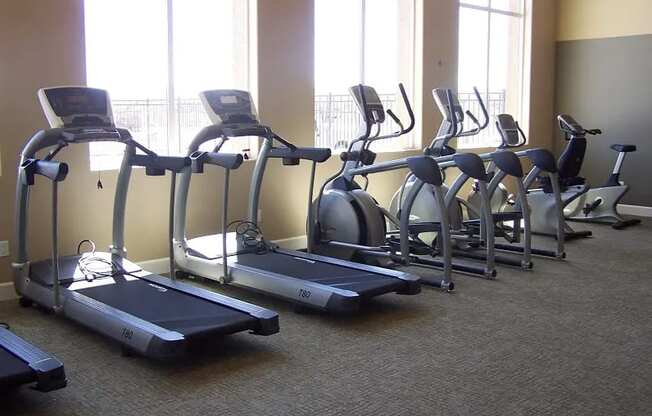 Reno, NV Apartments-Bungalows at Sky Vista-Fitness Center with Large Windows, Carpet Flooring, and Equipment