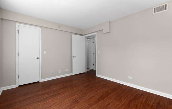 an empty living room with wood floors and white walls