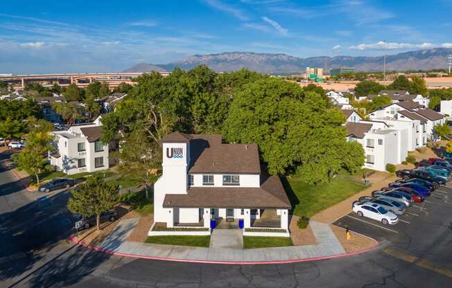 an aerial view of a large white house with a brown roof and a parking lot
