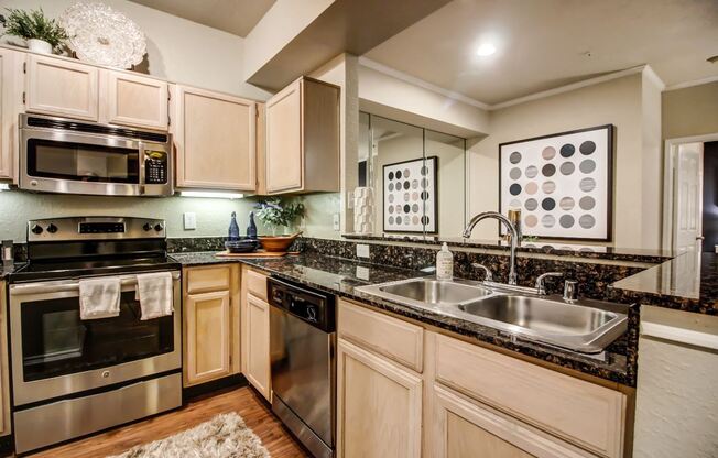 Stunning kitchen with hardwood style flooring, light colored cabinetry and stainless steel appliances