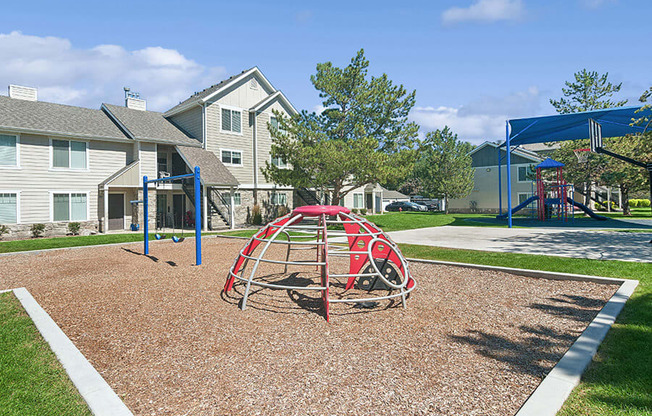 Community Playground with a Slide, Blue Canopy and Swing Set at Broadmoor Village Apartments located in West Jordan, UT.