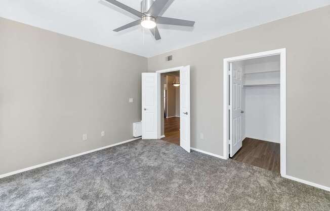 A room with a ceiling fan and two open doors.