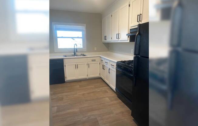 an empty kitchen with black appliances and white cabinets