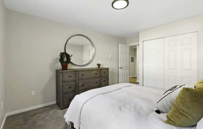 a bedroom with a white bed and a dresser with a potted plant