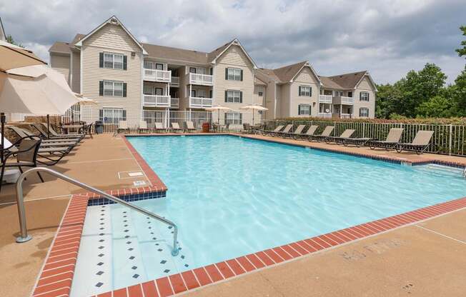 A swimming pool with a red brick border and a building in the background.at Summerland Heights, Woodbridge, 22191  