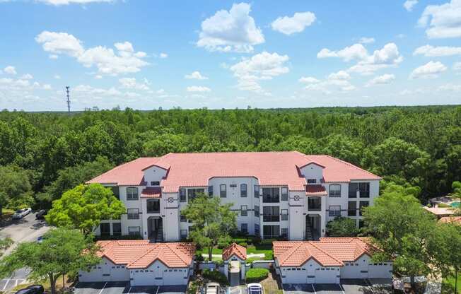 an aerial view of a building with a parking lot and trees