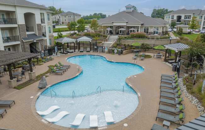 an aerial view of a large swimming pool with lounge chairs