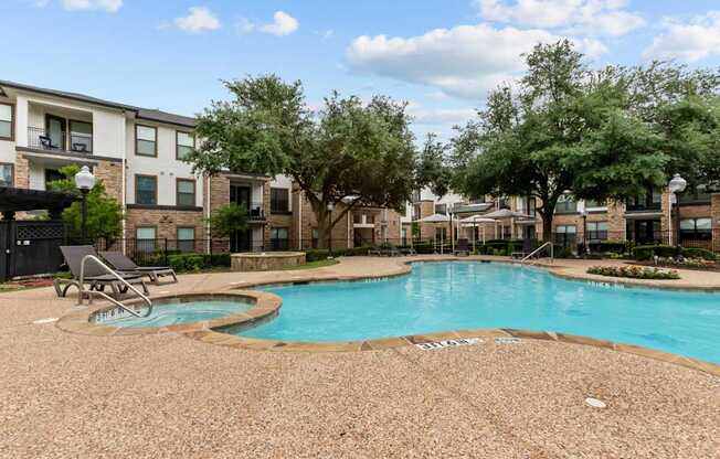 A swimming pool surrounded by a gravel area and trees.