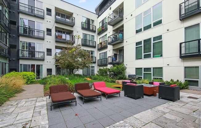 an outdoor area with lounge chairs in front of an apartment building