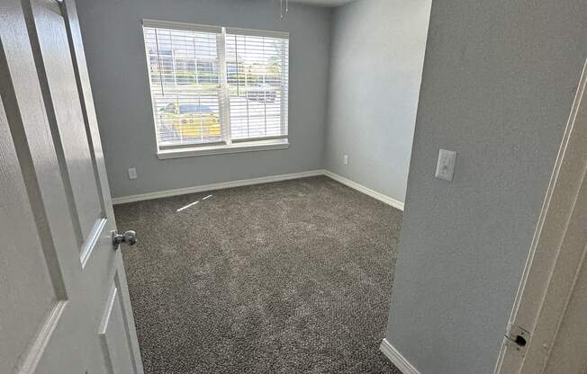 an empty room with a ceiling fan and a window