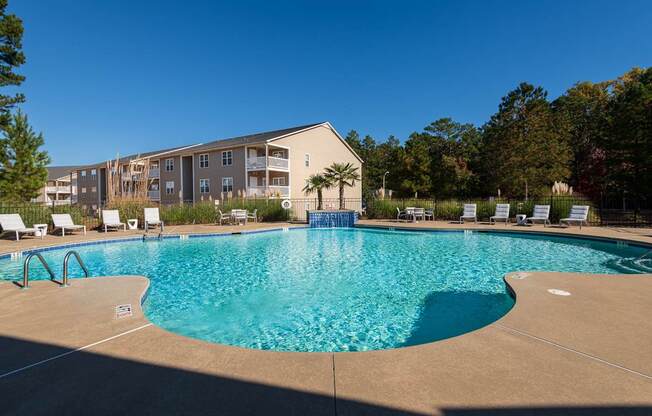 A large swimming pool in front of a building with a blue sky in the background.