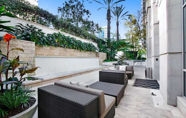 a patio with chairs and plants and a wall