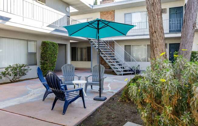 a patio with chairs and an umbrella in front of a building